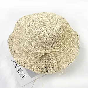 Top view of handwoven light beige straw sun hat with wavy brim and delicate ribbon bow