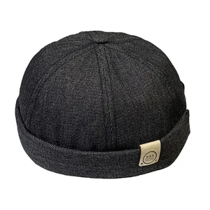 Bonnet docker unisexe en denim noir avec écusson en cuir vintage sur fond blanc