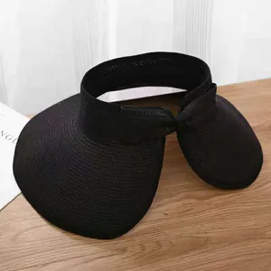 Detail of black straw visor with large brim and elegant bow on a rustic wooden table