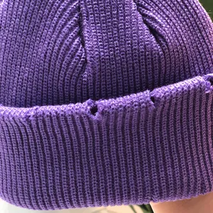 Primer plano del gorro de punto acanalado morado con detalles de rotos y textura