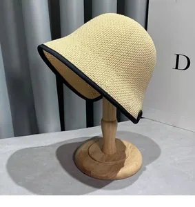 Detail of a beige woven cloche straw hat with black ribbon edge on a wooden stand