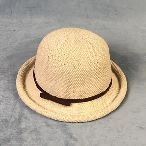 Dettaglio del cappello da sole beige in paglia intrecciata con nastro a fiocco marrone