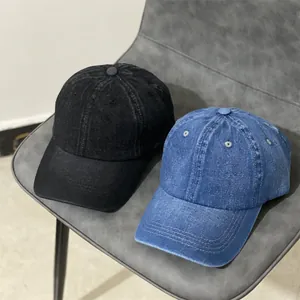 Détail de casquettes de baseball en denim délavé noir et bleu sur fond gris
