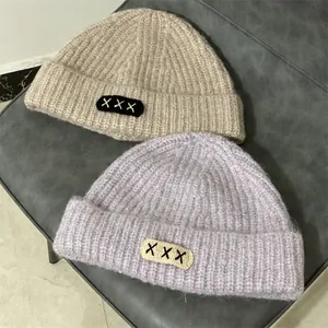 Chunky knit mohair beanies in beige and purple colors with embroidered patch detail