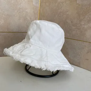 Dettaglio ravvicinato del cappello alla pescatora bianco con bordi sfrangiati e tesa