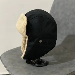Close-up of black aviator hat featuring warm beige faux shearling lining and metal buckle