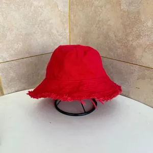 Dettaglio ravvicinato di un cappello a secchiello rosso con bordi sfilacciati alla moda