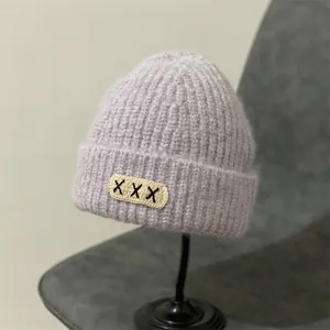 Close-up of light purple mohair knit beanie with folding brim and stitched XXX patch