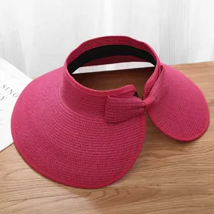 Macro view of rose red wide brim straw sun hat with decorative bow on a wooden surface
