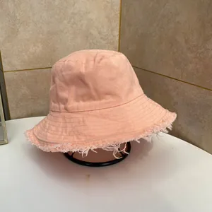 Dettaglio del cappello a secchiello in cotone arancione con bordi a frange e cuciture