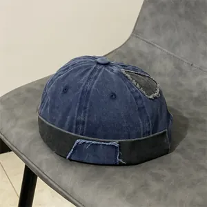 Dettaglio del berretto docker in denim vintage con patchwork usurato e bordo cucito