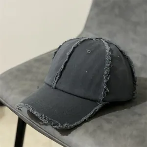 Détail d'une casquette gris foncé usée avec bords effilochés et texture de toile vintage