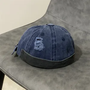 Dettaglio del berretto docker in denim blu con fori usurati e fibbia metallica regolabile