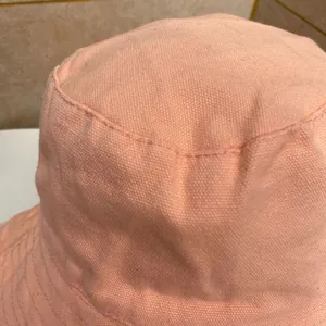 Dettaglio ravvicinato del cappello da sole in tela rosa con trama del tessuto e cuciture