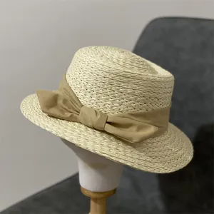 Chapeau de paille rétro français à large bord avec ruban kaki sur un support blanc