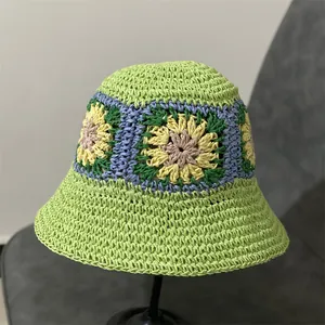 Gedetailleerde close-up van gehaakte bloemen op een groene strohoed voor dames in de zomer