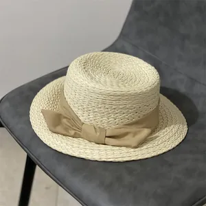 Détail d'un chapeau de paille avec un large ruban kaki sur une chaise en cuir sombre