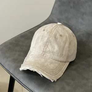Vintage washed khaki cotton baseball cap with distressed brim on leather seat