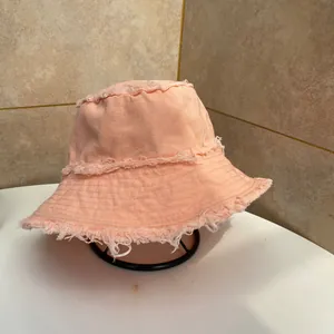 Dettaglio di un cappello da pescatore in tela rosa con bordi sfrangiati alla moda