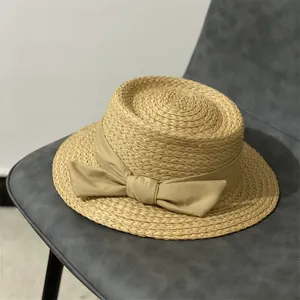 Détail d'un chapeau de paille élégant avec un grand nœud sur une chaise contemporaine