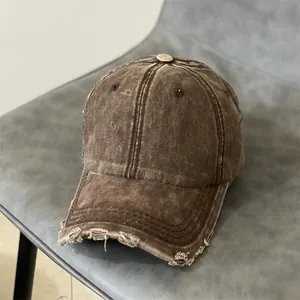 Detailed close-up of distressed washed denim baseball cap with frayed edges and brown finish