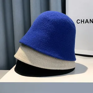 Three knitted bucket hats in royal blue, cream, and black showing thick textured weave
