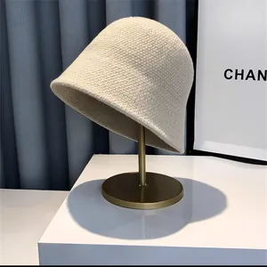 Detail view of apricot knit bucket hat showing thick wool texture on a metal stand