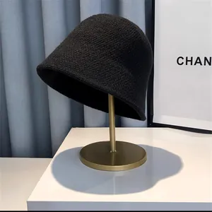 Detail view of black knit bucket hat on a gold metal stand for winter season