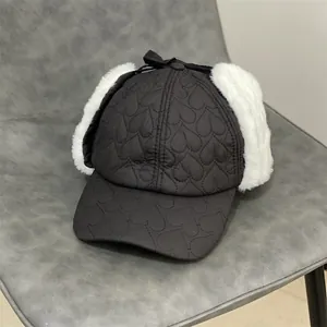 Detail view of heart-quilted winter bomber hat with faux fur earflaps and bow decoration