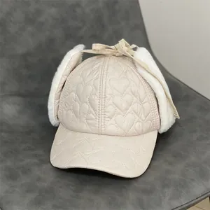 Detail of beige winter earflap hat featuring heart-shaped quilting and faux fur lining