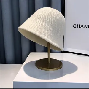 Macro view of white knitted bucket hat with dense wool texture on a gold stand