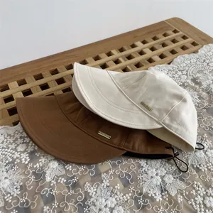Wide brim wool bucket hat in beige and brown with adjustable strap and metal branding