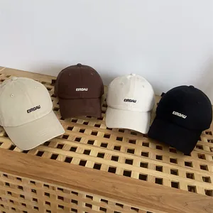 Neutrale Baumwoll-Basecaps mit EIRDAU-Stickerei in vier Farben auf einem Holzregal präsentiert