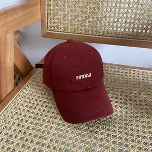 Detailaufnahme der weißen EIROAU-Stickerei auf weinrotem Baumwoll-Canvas-Baseballcap