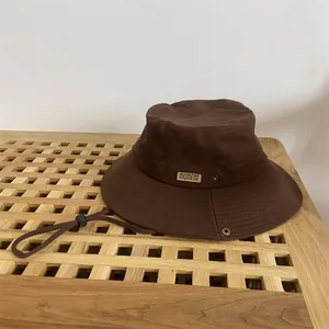 Detailed view of coffee bucket hat with MOMENT leather patch and adjustable chin strap