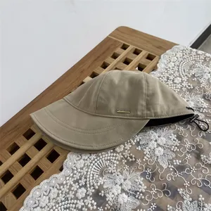 Detail of khaki wool bucket hat featuring metallic logo plaque and adjustable drawstring