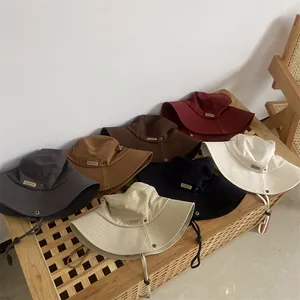 Detail view of cotton bucket hats in various colors with leather MOMENT tags