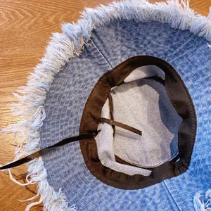 Detailed interior of denim sun hat with frayed edges and adjustable sweatband strap