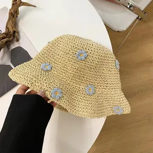 Breathable beige straw bucket hat with delicate blue floral accents for summer beach vacation
