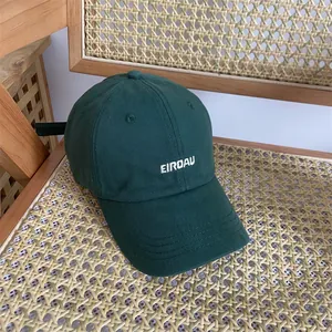 Detail einer dunkelgrünen Baumwoll-Basecap mit weißer EIRDAU-Stickerei auf einem Korbstuhl