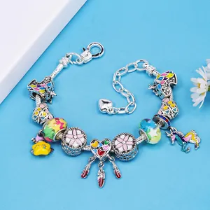Pulsera de cadena de serpiente plateada con dijes de unicornio y corazón sobre fondo azul