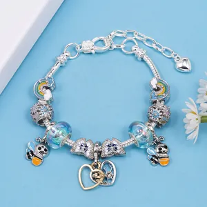 DIY colorful bee charm bracelet with silver snake chain and heart pendant on blue background