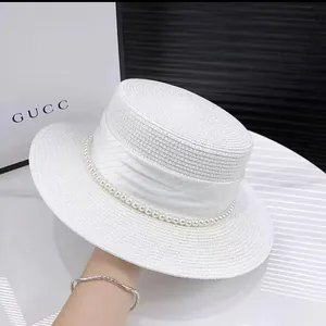 Detailed close-up of wide brim straw sun hat with elegant pearl embellishments and white ribbon