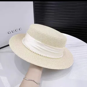 Flat top boater straw hat featuring a wide white ribbon and elegant pearl trim detail