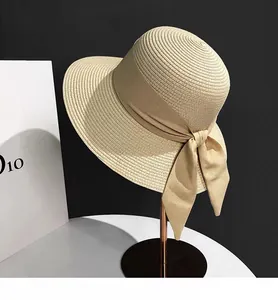 Detail view of the elegant woven straw sun hat with a large bow on a metal stand