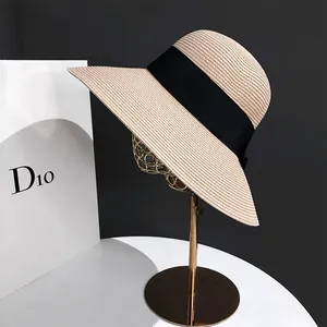 Détail d'un chapeau de paille à larges bords avec ruban noir sur support vintage