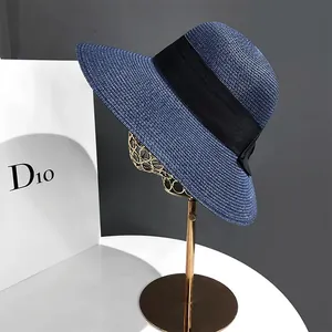 Détail d'un chapeau de soleil bleu en paille à large bord avec un élégant ruban noir