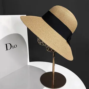 Détail de chapeau de paille tressé avec ruban gros-grain noir et noeud sur support métallique