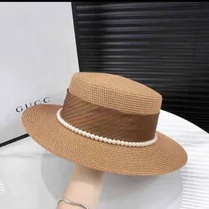 Detailed view of handmade straw hat featuring elegant ribbon and white pearl trim embellishment