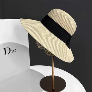Détail d'un chapeau de paille beige avec ruban noir sur support doré